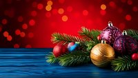 Festive Christmas ornaments and pine branches on blue wooden surface against red bokeh background for holiday greeting cards.