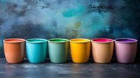 Colorful ceramic mugs arranged in rainbow order against dark textured background with turquoise highlights, creating modern minimalist composition for kitchen and cafe decor.