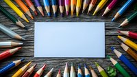 Colorful sharpened pencils arranged in circle around blank white card on wooden surface, creative workspace setup for art, design, education, and back-to-school projects.