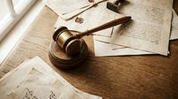 Wooden judge gavel resting on antique legal documents with wax seals on rustic wooden table, symbolizing law, justice, and authority.