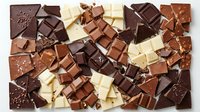 Assorted chocolate pieces in dark, milk, and white varieties arranged flat lay on white background, suitable for food, confectionery, and culinary design projects.
