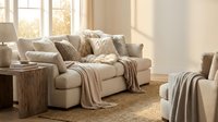 Cozy beige living room interior with comfortable sofa, soft throws, pillows and warm natural lighting creating relaxing home atmosphere for design projects.