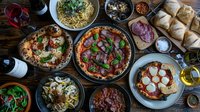 Traditional Italian pizzas and pasta dishes served on rustic wooden table, including Neapolitan style margherita, prosciutto, and mushroom varieties with fresh ingredients and authentic presentation.