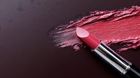 Pink lipstick with smeared makeup texture on dark background for beauty and cosmetics advertising campaigns.