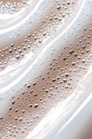 Water droplets and condensation on smooth curved surface creating abstract diagonal pattern in soft beige and white tones. Macro photography for backgrounds.