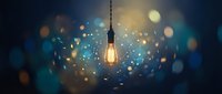 Vintage Edison bulb glowing warmly against dark blue background with magical bokeh lights creating atmospheric illumination for creative projects.