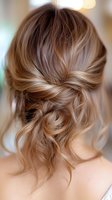 Elegant loose updo hairstyle with soft honey blonde highlights and romantic twisted details, showcasing modern bridal hair styling trends for special occasions.