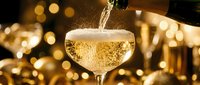 Champagne pouring into coupe glass with golden bokeh lights in background, celebration and festive occasion beverage.