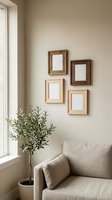 Minimalist living room with four wooden frames mockup on beige wall, cozy sofa, and olive tree plant by window in neutral tones.
