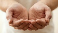Open cupped hands in protective gesture showing care, support and offering help in warm natural lighting for wellness and charity concepts.