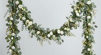 Wedding garland with white roses and eucalyptus leaves on neutral background for bridal decoration and event styling purposes.