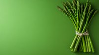 Fresh green asparagus bunch tied with twine on vibrant green background with copy space. Clean minimalist food photography for healthy eating concept.