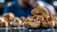 Roasted cashew nuts macro shot with selective focus showing detailed texture and natural golden color on dark background, suitable for food packaging design.