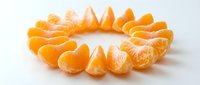 Peeled mandarin orange segments arranged in a circle on white background, showcasing fresh citrus fruit slices in a creative flat lay composition.
