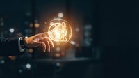 Businessman hand holding glowing light bulb with digital network connections against blurred city background, representing innovation and creative business solutions.