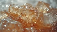 Extreme close-up of melting ice cubes in cola drink showing carbonation bubbles and refreshing condensation droplets with soft bokeh lighting effect.