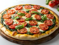 Fresh homemade pizza with pesto sauce, sliced tomatoes, melted mozzarella and basil leaves on wooden cutting board, close up view of traditional Italian cuisine.