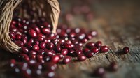 Fresh red cranberries spilling from woven basket onto rustic wooden surface, creating natural composition with selective focus and soft bokeh background.