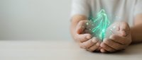 Hands holding glowing green holographic brain with digital particles, representing artificial intelligence, neuroscience, mental health and innovative technology concepts.