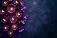 Glowing purple candles with flower petals on dark textured background, creating serene atmosphere for spa, meditation, or spiritual practices.