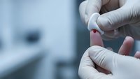Medical professional in white gloves holding blood sample drop for laboratory testing and diagnostic analysis in clinical healthcare setting.