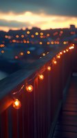 String lights illuminate wooden railing at dusk, creating warm ambiance against blurred city bokeh lights and sunset sky background.