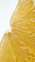 Extreme macro closeup of a juicy lemon slice showing translucent yellow pulp segments with glistening moisture drops on white background.