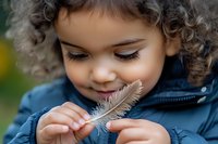 Curious mixed-race toddler girl with curly hair examining white feather outdoors, wearing blue jacket. Child exploring nature, discovery learning concept.