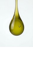 Isolated golden-yellow oil droplet suspended against white background, showcasing liquid texture and translucency for cosmetic, skincare, and wellness design applications.