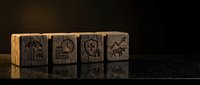 Ancient wooden cubes with carved hieroglyphic symbols on dark reflective surface for educational and historical design projects.