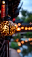 Ornate glowing lantern with intricate floral cutout pattern illuminated at dusk, with string of warm lights creating magical bokeh effect in background.