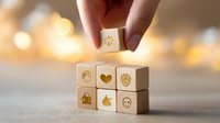 Wooden blocks with wellness and mindfulness symbols arranged on light surface with bokeh background, hand placing top cube for mental health concept.