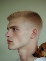 Young Caucasian man with trendy fade haircut in profile view holding small brown dog, modern barbershop styling for grooming and pet care concepts.