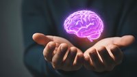 Businessman holding glowing purple brain hologram in cupped hands representing artificial intelligence, innovation and mental health concepts.