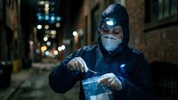 Professional welder in protective mask working with bright blue welding torch on metal construction project at night in urban industrial setting.