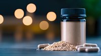 Dietary supplement powder in jar with capsules and raw ingredients against blurred bokeh background, wellness and health concept photography.