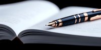 Elegant fountain pen with gold accents resting on open book pages in dramatic lighting, creating professional atmosphere for business and education concepts.