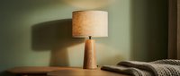 Wooden table lamp with linen shade casting warm light in minimalist interior setting, suitable for home decor and design projects.