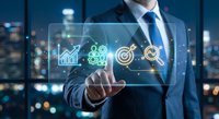 Professional businessman touching digital interface with business analytics icons including growth charts and target symbols in modern office setting.