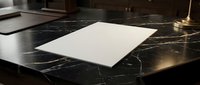 Blank white paper sheet on a dark marble desk surface in an elegant office setting, ready for text or document mockup use.