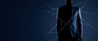 Silhouette of businessman in suit surrounded by glowing network connections and digital lines on dark blue background, representing corporate networking and technology integration.