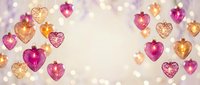 Romantic heart-shaped ornaments in pink, gold and purple tones with soft bokeh lights creating festive Valentine's Day or wedding celebration background.