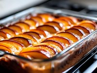 Freshly baked sausages arranged in rows within a metal baking tray, displaying golden-brown caramelized skin with glistening moisture, perfect for food photography, culinary blogs, restaurant menus, and cooking publications.