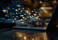 Hands typing on laptop keyboard with glowing digital data blocks floating above in dark room, representing cyber security and data transfer technology.