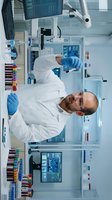 Male scientist in white lab coat and blue gloves conducting research in modern laboratory with test tubes and digital displays, suitable for healthcare and scientific publications.