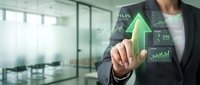 Businessman touching virtual financial dashboard with green growth arrow and stock charts showing positive market trends in modern office.