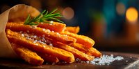 Golden crispy french fries with sea salt and fresh rosemary garnish served in paper cone on wooden surface with warm bokeh background for food photography.