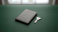 Closed gray leather wallet with silver key on green surface, symbolizing security, savings, and financial protection for business concepts.