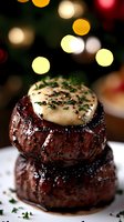 Grilled filet mignon steaks topped with herb butter sauce and black pepper, stacked against festive holiday lights background. Gourmet dinner presentation.