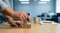 Male hand arranging wooden blocks with business icons on office desk, representing strategy, planning, and corporate growth in modern workplace environment.